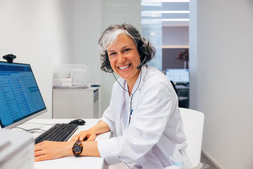 An interpreter wearing a headset smiles at her workstation